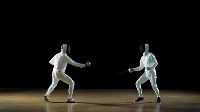 Two Professional Fencers Expertly Fight with Foils. Shot Isolated on Black Background. 