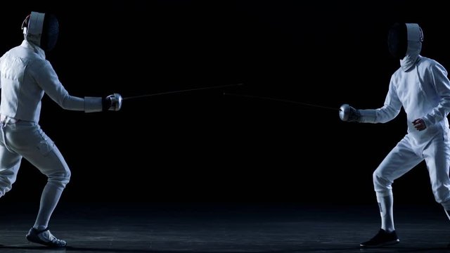 Two Professional Fencers Show Masterful Swordsmanship in their Foil Fight. One Fencer Recaptures Quick Fleche Attack. Shot Isolated on Black Background  with Cold Tones and Slow Motion.