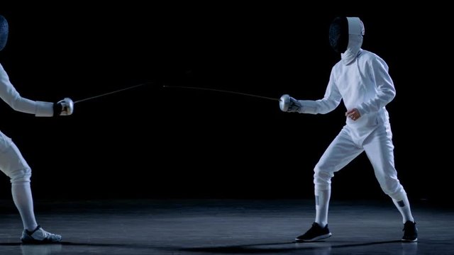 Two Professional Fencers Show Masterful Swordsmanship in their Foil Fight. They Dodge, Leap and Thrust and Lunge. Shot Isolated on Black Background  and in Slow Motion.