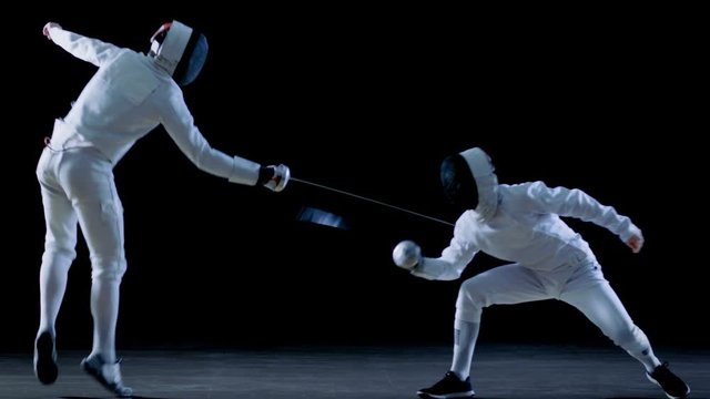 Two Professional Fencers Show Masterful Swordsmanship in their Foil Fight. They Dodge, Leap and Thrust and Lunge. 