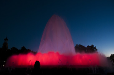 Silhouette of person taking a photo of a Large colourful Water Fountain display