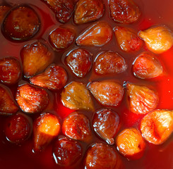 Fig jam or jelly cooking process. Brilliant figs in syrup, close-up. The fig jam is boiling, shiny berries in liquid. Boiling figs with sugar for jam or preserves preparation. 