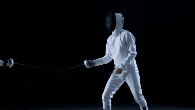 Two Professional Fencers Show Masterful Swordsmanship in their Foil Fight. They Leap and Thrust and Lunge. Shot Isolated on Black Background. Shot on RED EPIC-W 8K Helium Cinema Camera.