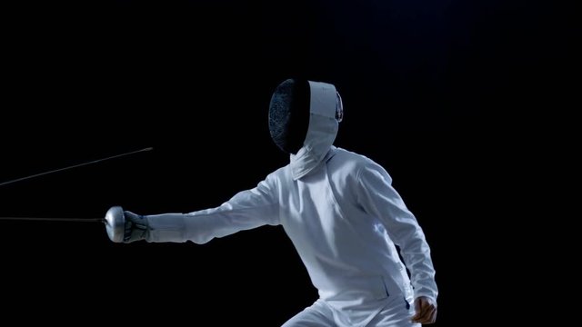 Two Professional Fencers Show Masterful Swordsmanship in their Foil Fight. They Attack, Defend, Leap and Thrust and Lunge. Shot Isolated on Black Background  and in Slow Motion. 