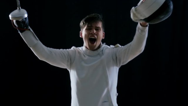 Two Professional Fully Equipped Fencers Expertly Fight with Foils. One Lunges and Wins, He Takes of His Mask in all the Glory. Shot in Slow Motion and on Isolated Black Background. 