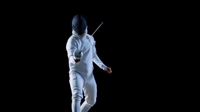 Portrait Shot of a Fully Equipped Skilled Fencer Training with a Foil. He Practices Attack, defense,  Leap, Thrust and Lunge. Shot Isolated on Black Background. 