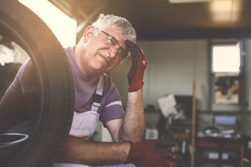 Senior man in workshop. Man having headache after hard work.