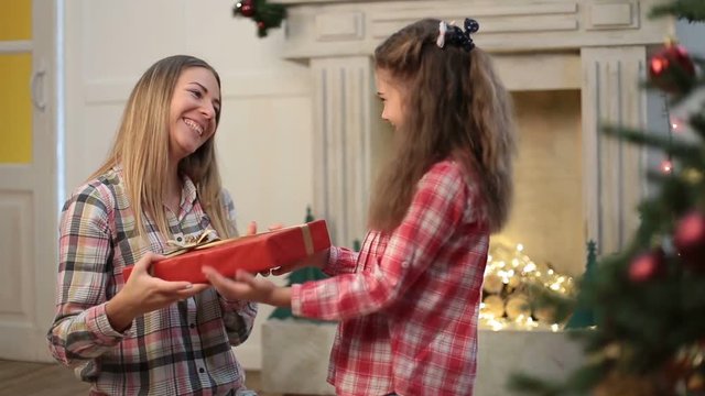 Cute daughter giving Christmas gift to mother