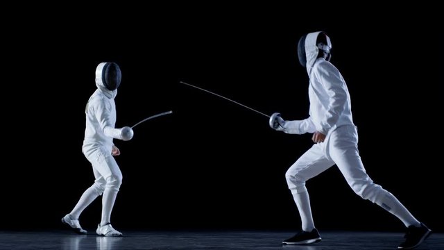 Two Professional Fully Equipped Fencers Expertly Fight with Foils. They Attack, Defend, Leap, Thrust and Lunge. Shot in Slow Motion and on Isolated Black Background. 