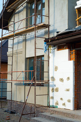 Reconstruction of private house, installing thermal insulation for walls with scaffoldings