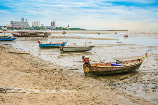 small fishing boat on beach with cityscape and bright sky background, Pattaya City, Thailand