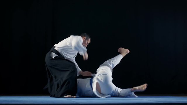 Martial Arts Master Wearing Hakamas Teaches Young Student  Aikido Technique. Shot Isolated on Black Background and in Slow Motion. 