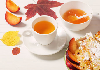 pancakes with tea  and plums on white wooden table