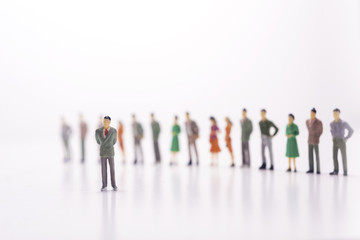 Miniature people, boss against the line of people over white background.