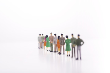 Miniature people standing in line over white background.