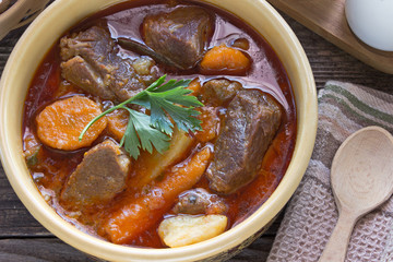 Stew with meat and vegetable in ceramic bowl on table