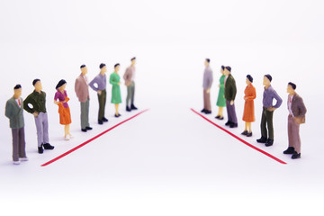 Miniature people in two lines across to each other over white background.