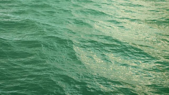 Fly over green ocean surface in slow motion, loopable