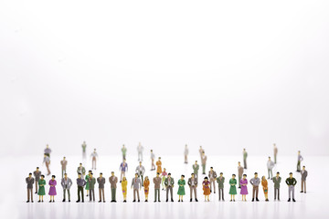 Group of miniature people over white background standing in line.