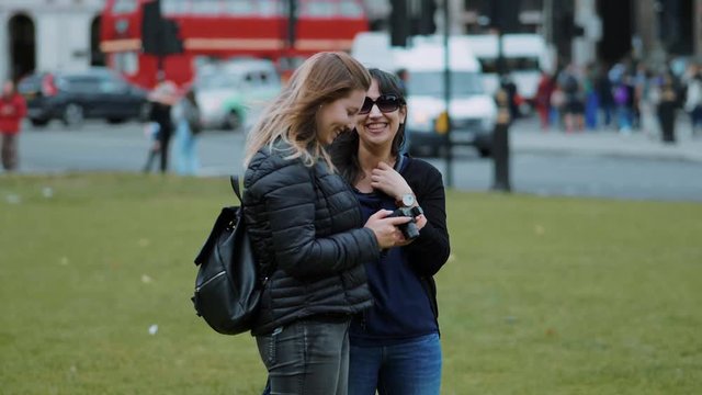 Two young women check photos on the camera - London sightseeing in slow motion