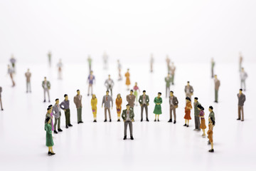 Group of miniature people over white background standing in line or circle.