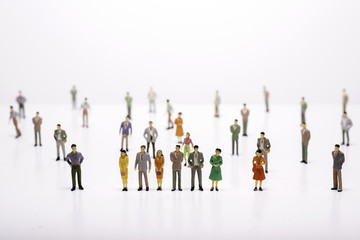 Group of miniature people over white background standing in line or circle.