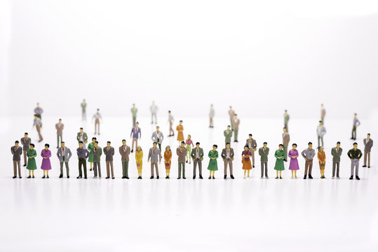 Group of miniature people over white background standing in line.