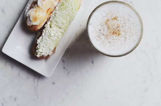Latte and delicious eclairs with copy space on marble background