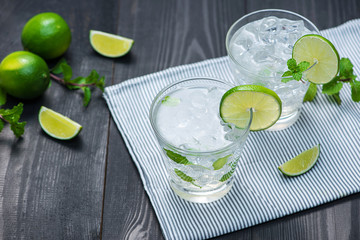 Fresh cocktail with lime, ice and mint on a rustic background. Copy space, top view