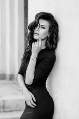 Portrait of an attractive brunette in a black dress. Fashion photo. Black-and-white photo.