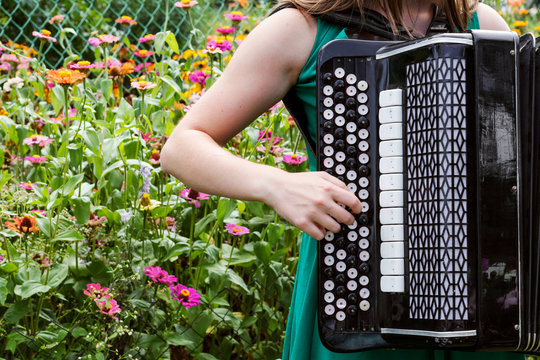 Girl musician plays the the Russian bayan (button accordion) and singing.