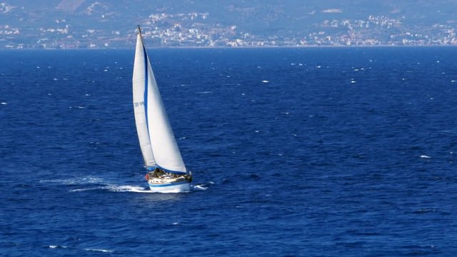 Panning shot of a yacht sailing on the Mediterranean sea, off the coast of Crete.