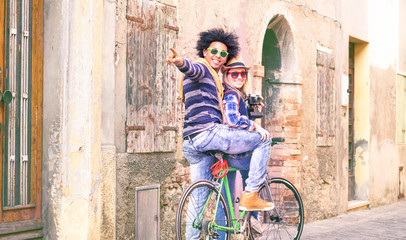 Fototapeta na wymiar Interracial couple of tourists riding bike in old and town and pointing finger