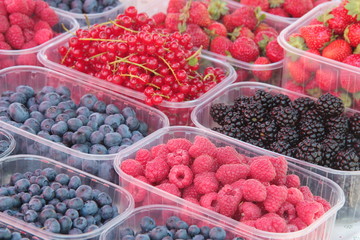 Raspberries, blueberries, blackberries, Currants and Strawberries put in plastic baskets in a local food market stall 