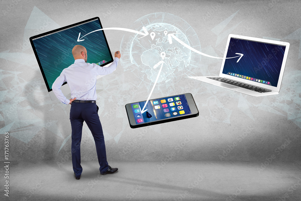 Poster businessman in front of a wall with computer and devices displayed on a futuristic interface with in