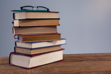 Spectacles and pencil on book stack