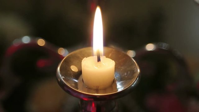 One candle on a table on a black background blazes