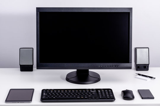 Blank black pc monitor on desktop in organized workplace.