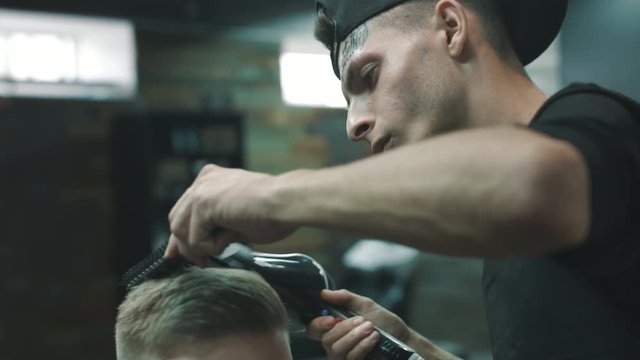 Barber makes the blow-dry after cutting a client's hair in a barbershop. Close.