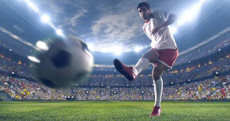 Soccer player kicks the ball on the soccer stadium. He wear unbranded sports clothes. Stadium and...