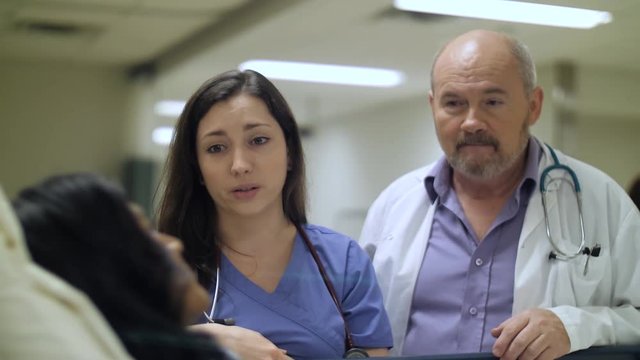 Caring doctor and nurse deliver bad news to a patient bedside in hospital.
