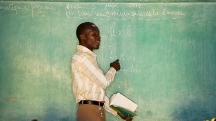 A young teacher writes math equations on a blackboard and teaches a classroom - Powered by Adobe