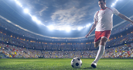 Soccer player kicks the ball on the soccer stadium. He wear unbranded sports clothes. Stadium and...