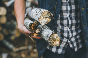 Lumberjack holding a chopping wood. Birch firewood in his hands.
