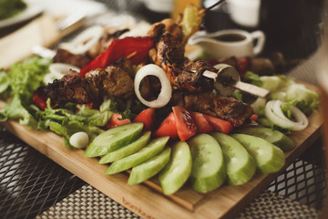 Skewered on sticks tasty pork meat and vegetables mix, grilled meat on wood plate