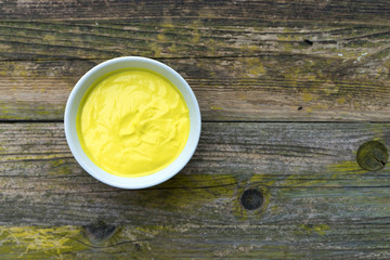 Mayonnaise sauce in a bowl on wooden background.