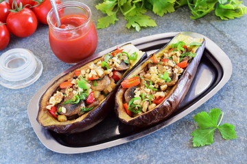 Eggplants stuffed with mushrooms, onions, carrots, tomatoes and nuts on a metal plate on a grey background. Vegetarian food. healthy eating concept.