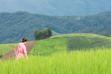Fototapeta na wymiar Asian woman relaxing in rice terraces fields on holiday