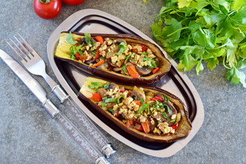 Eggplants stuffed with mushrooms, onions, carrots, tomatoes and nuts on a metal plate on a grey background. Vegetarian food. healthy eating concept.