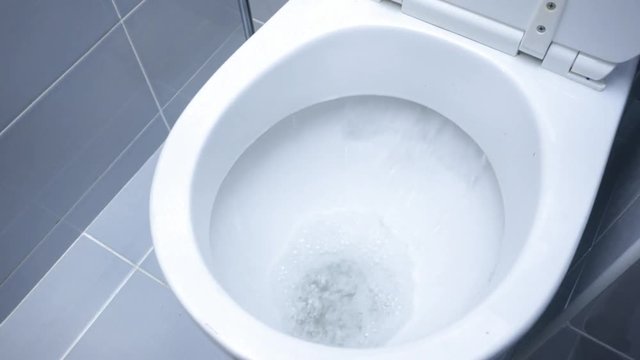 Morning starts not with a coffee. Closeup video of a flushing white toilet.